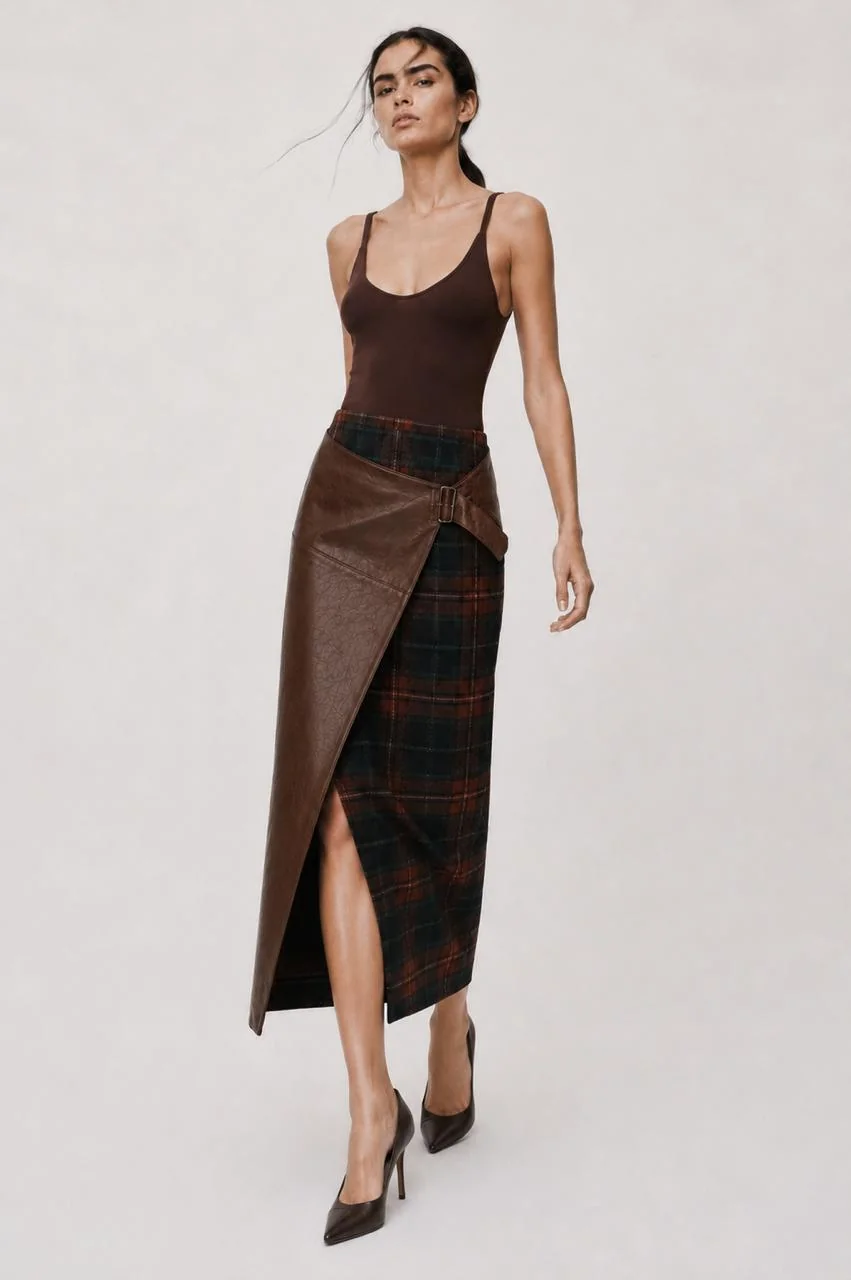 Full front view — the chestnut leather wrap buckled over the plaid midi, worn with a brown tank and heels.