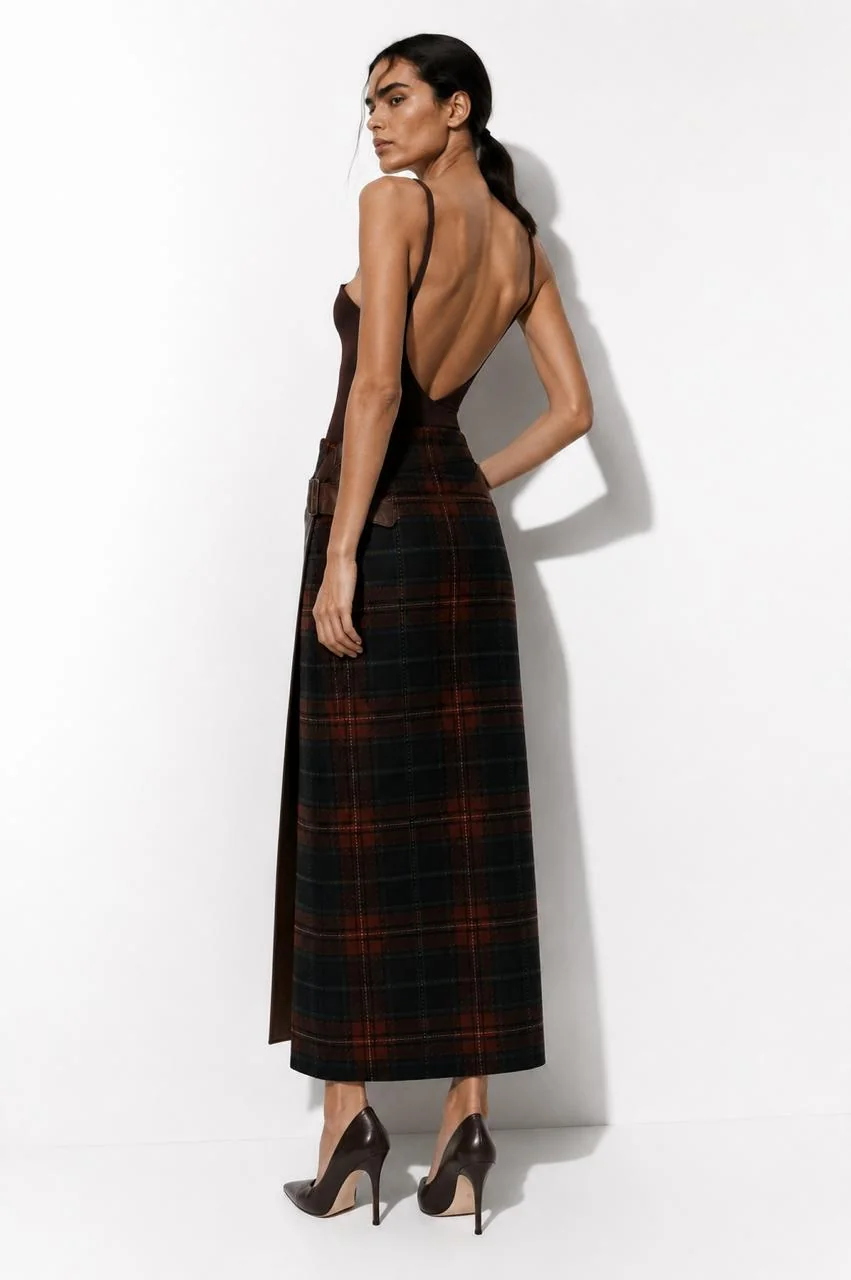 Back view in heels — the plaid back panel with the leather flap edge visible at the side seam.