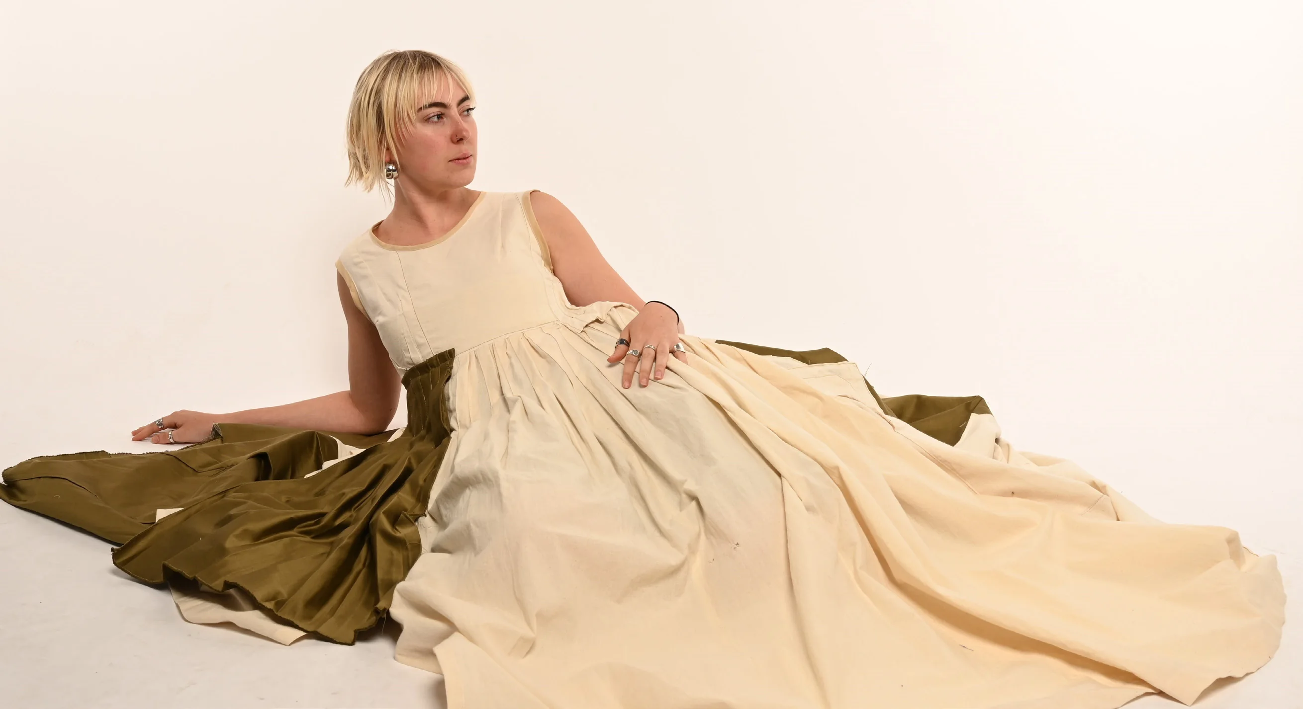 Full Circle cover — the model reclining in the cream cotton gown with its olive silk train spread across the studio floor.
