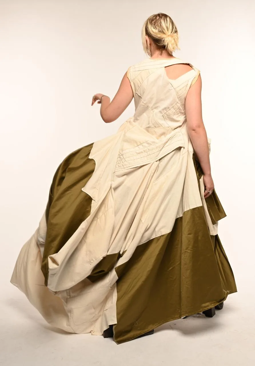 Back view mid-stride, arm raised, the olive silk train sweeping across the floor behind the cream bodice.