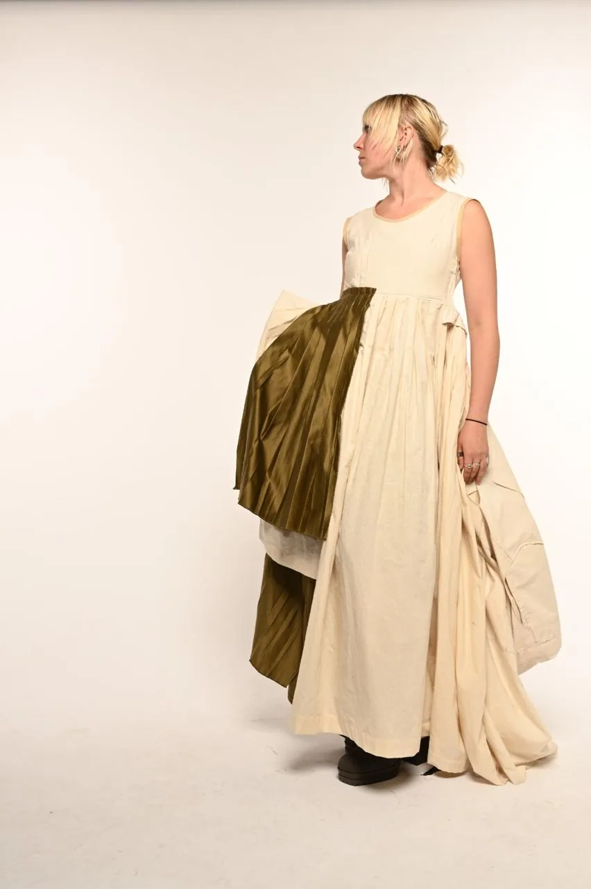 Side-back view walking, gathering the cream cotton panels with the olive silk train trailing behind.